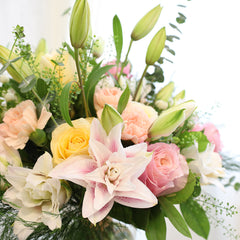 Bouquet of Oriental Lilies, Flamingo Roses, Creme De La Creme Roses, Hypericum, and Carnations with Eucalyptus, Lemon Leaves, Green Tree Fern, and Thlasip greeneries.